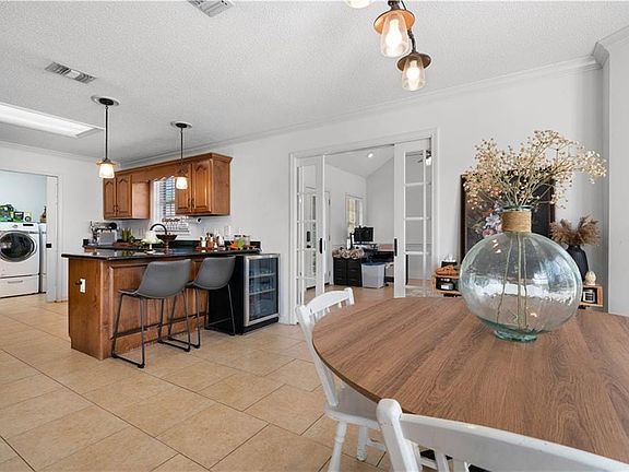 Dining area with french doors, ornamental molding, a textured ceiling, light tile patterned flooring, and washer / dryer
