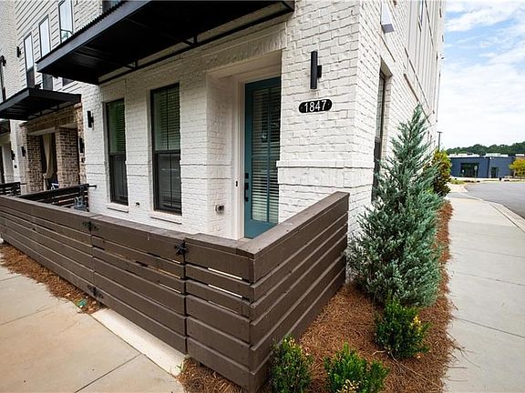 STATELY END UNIT OF WHITE-PAINTED BRICK, FENCED GATE ENTRY, AND BEAUTIFUL LARGE WINDOWS PROVIDING LI