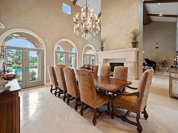 The formal living and dining rooms feature 23 ft. ceilings, two sided fireplace, beautiful wood beam ceiling, Travertine tile and French doors that lead to the pool and outdoor living area.