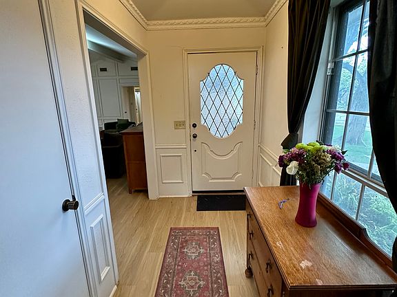 Entryway with wainscoting, light wood-type flooring and ornamental molding