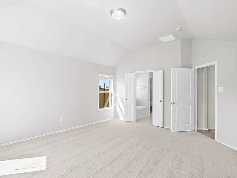 Spacious primary bedroom with plush carpet and double doors leading to the ensuite bath and walk-in closet.