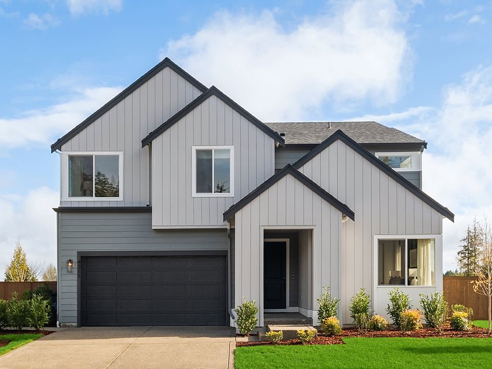 A modern two-story house with a gray exterior, a black garage door, and a well-manicured lawn in the