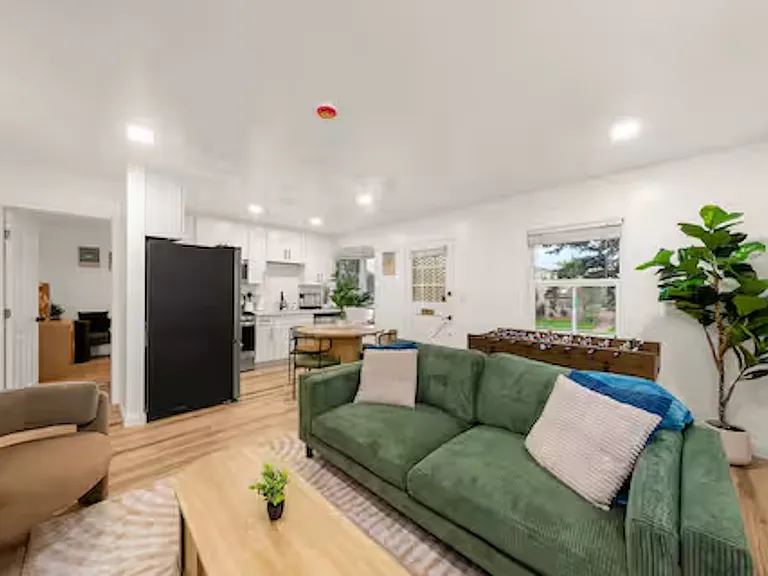 Inviting living room with comfortable seating, a 55" TV, plenty of natural light, and a mini-split AC for year-round comfort, featuring a game table and board games. Perfect space for family and friends to relax, socialize, and play together.