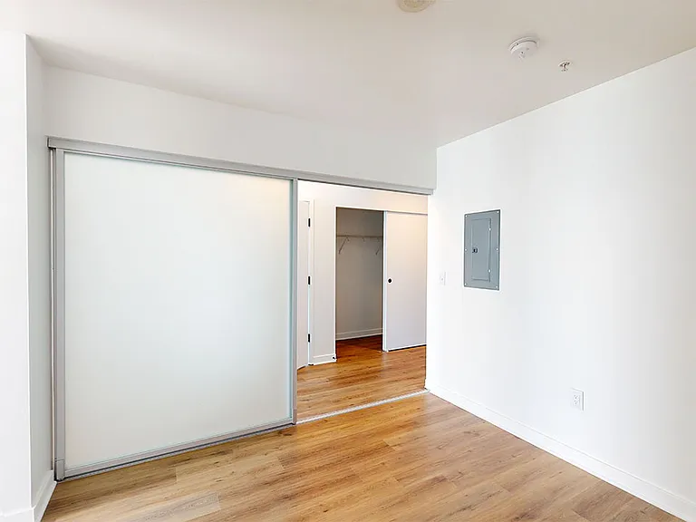 Spacious apartment bedroom with wood-style flooring.