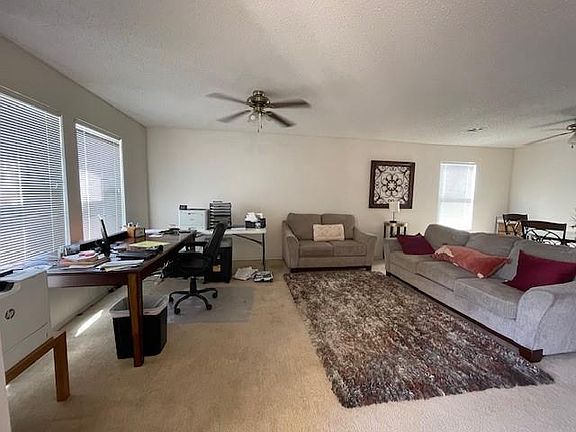 Carpeted home office featuring ceiling fan and a textured ceiling