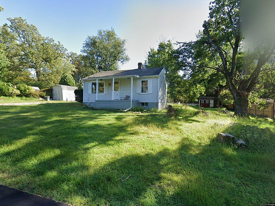 View of the front door from the road. To the left you can see the large driveway, featuring a shed for additional storage.