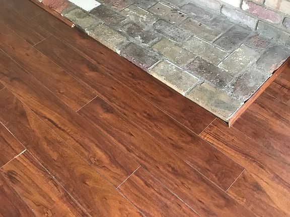 Bottom of full brick fireplace, and beautiful flooring in the living room.