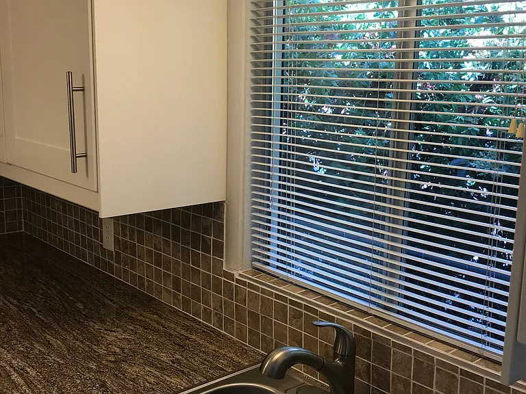 kitchen sink with pull-out faucet, soap dispenser and granite countertops with tile backsplash