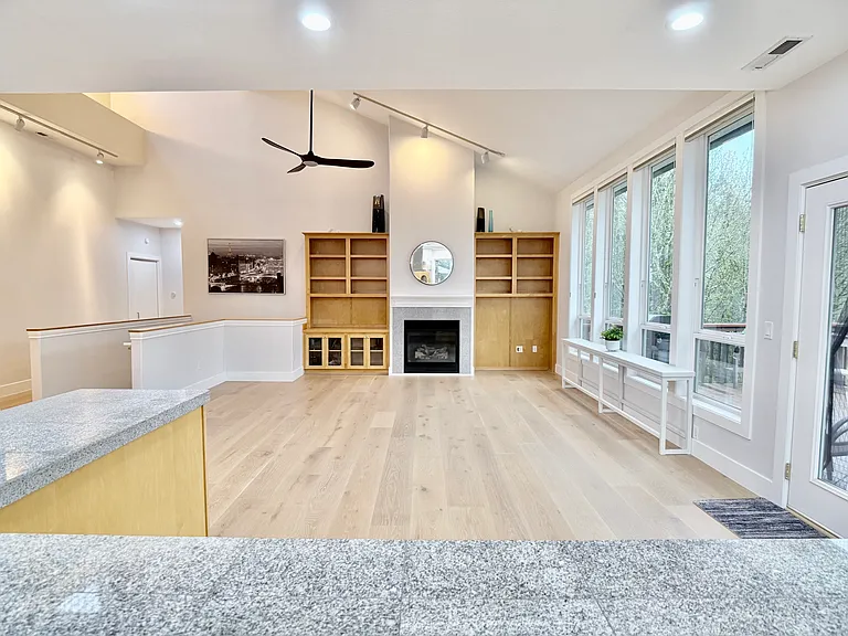 Large secondary living space with gas fireplace, ceiling fan, built-ins, forested views, lots of natural light, access to partially covered deck.