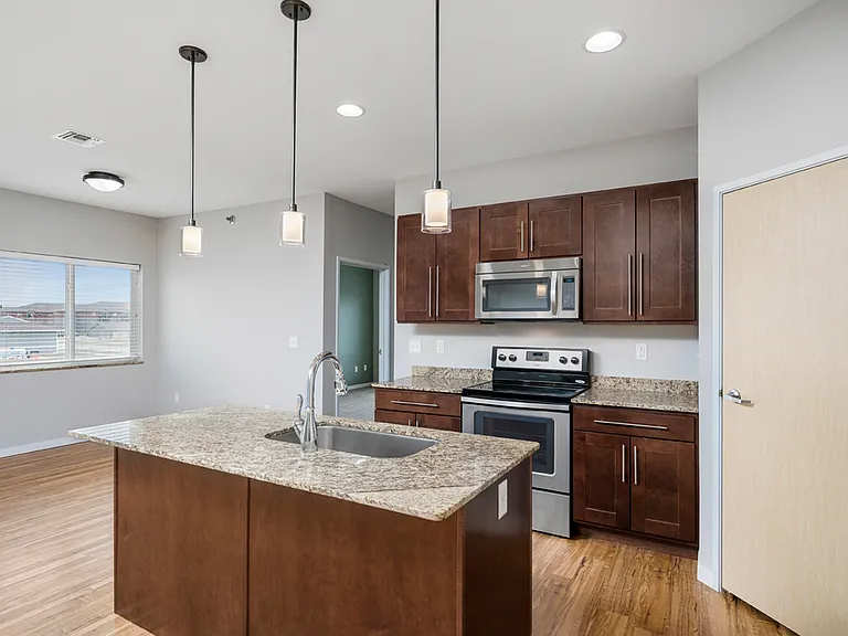 Modern kitchen design with granite countertops, stainless steel appliances, and elegant pendant lighting in a bright and spacious open layout. Modern kitchen design with granite countertops, stainless steel appliances, and elegant pendant lighting in a br