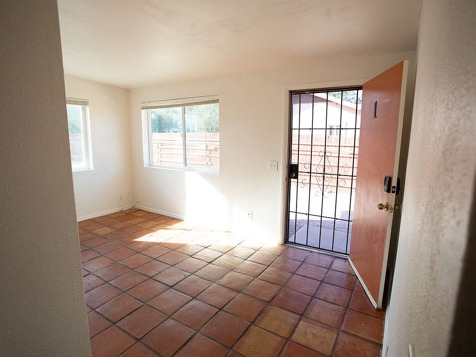 Abundant natural light pours through the living room's large windows, highlighting the handmade saltillo tile underfoot. This bright, open space creates an atmosphere where you can truly breathe and settle in.