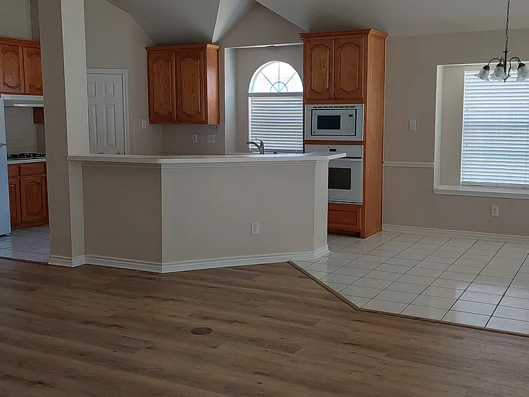 Looking across open living area to kitchen, nook, and peeking into formal dining room. Original tile left in kitchen and nook. All other rooms have luxury vinyl tile flooring 7/20/2026
