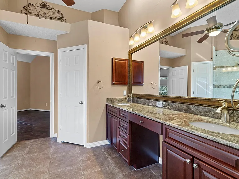 Double vanity with granite countertops, wood cabinetry, and a full-width mirror