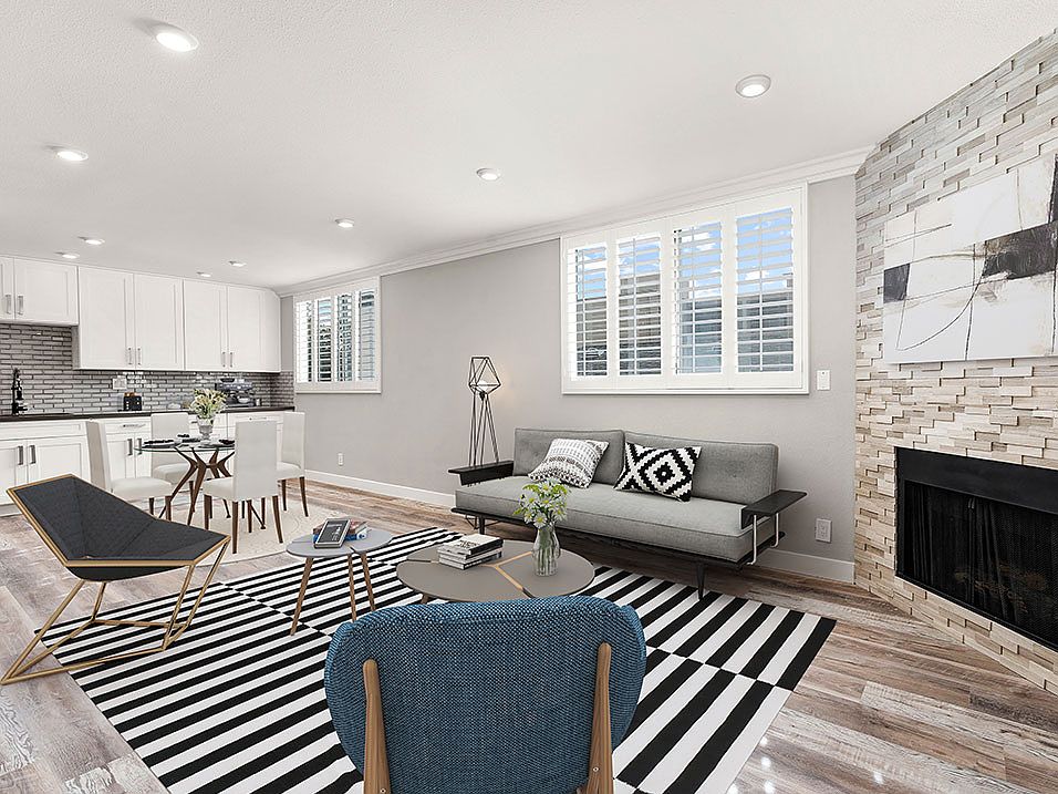 Hardwood floored living room with large windows and stone-accented fireplace.