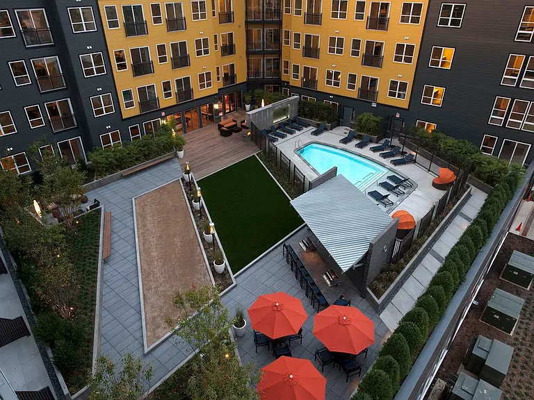 Courtyard with swimming pool and sundeck with lounge seating, greenspace