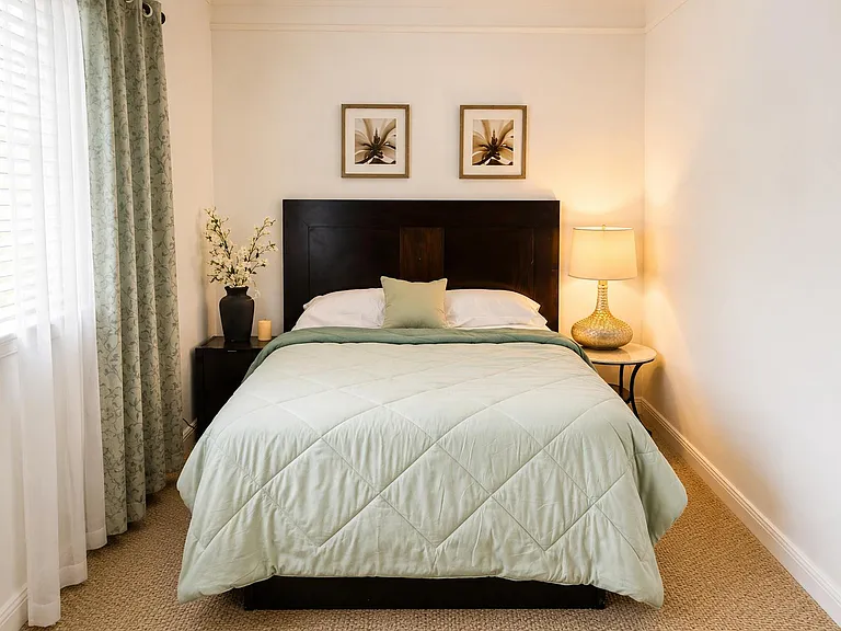 Well-appointed bedroom with a full bed, bedside lighting, and window with curtains for comfortable daily living.