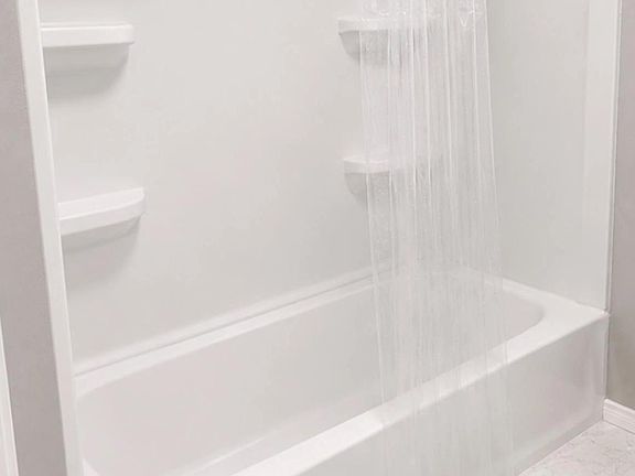 Tub/shower combo with built-in shelving and an overhead rainfall showerhead for everyday convenience.