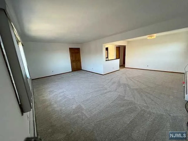 View of open plan living room and dining room. 2nd entrance door on left while to the right you walk either into the kitchen or down the hallway