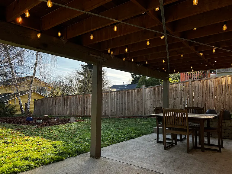 The backyard patio is all yours, and is complete with cafe lights and a teak dining table and chairs.