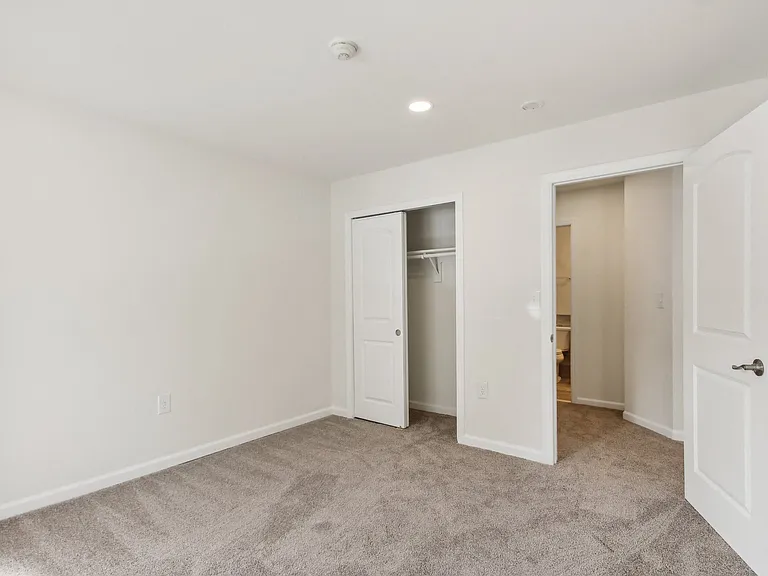 a bedroom with white walls and a door to a closet