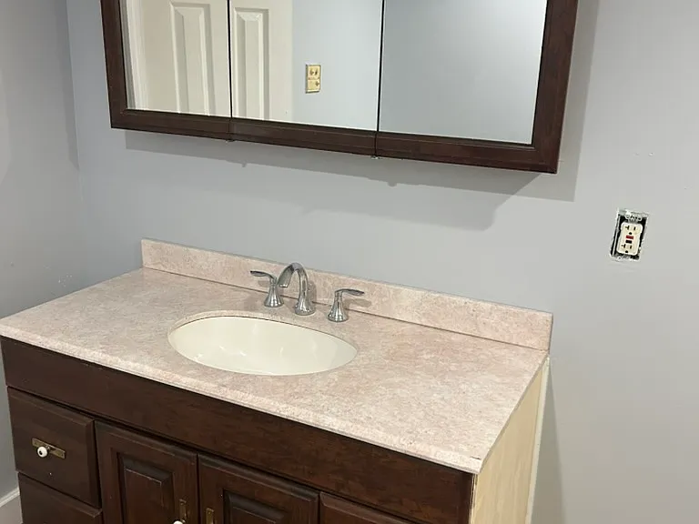 Bathroom with cultured marble countertop, mirrored cabinet, and lots of storage.