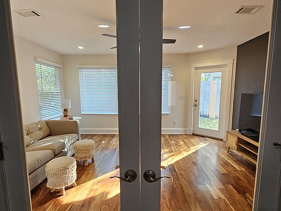 Family room with glass French doors. The wall on the right is set up with a wall mount to hang a TV.