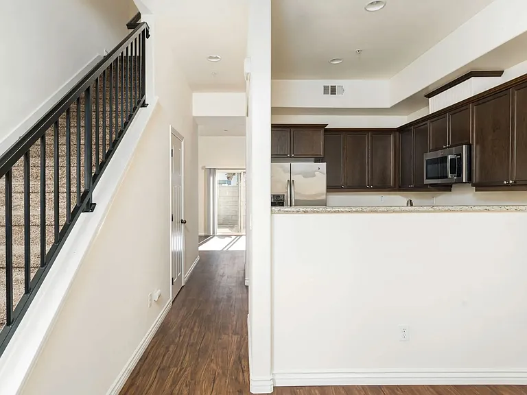 Front entrance view of kitchen and hallway to living room and sliding glass doors to private porch at The Nines Townhomes in Escondido, California.