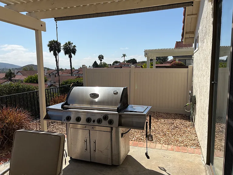 Outdoor side yard with Vermont Casting Propane grill and newly installed vinyl fence.