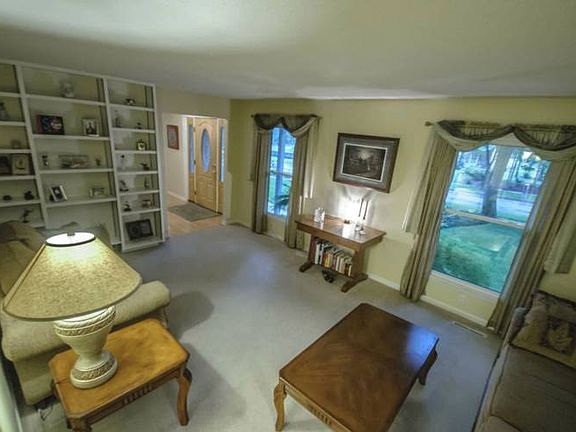 Lovely living room (20x12) with views of the front yard, built in shelving, and neutral carpeting.