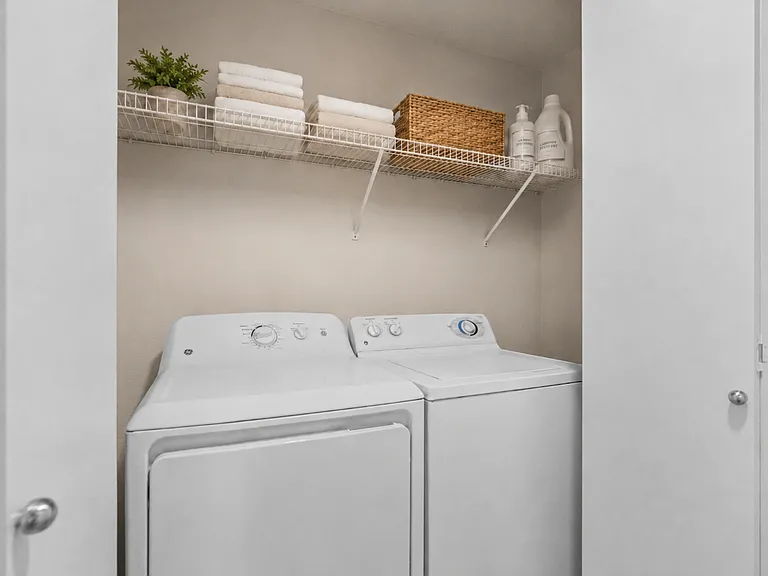 A convenient in-home laundry space with a full-size washer and dryer, plus overhead shelving for towels and everyday essentials. A convenient in-home laundry space with a full-size washer and dryer, plus overhead shelving for towels and everyday essential