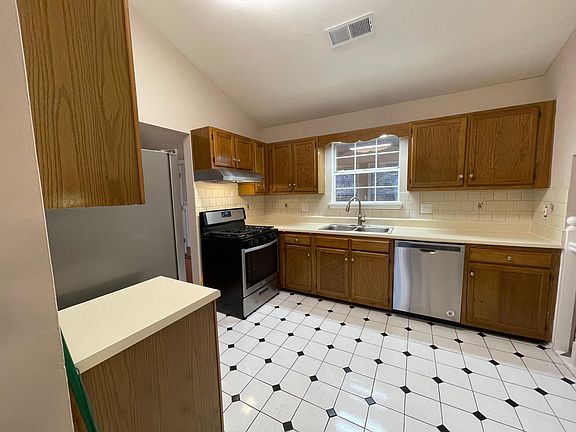 Kitchen view from foyer. New stainless steel Whirlpool dishwasher, gas oven, and refrigerator. Garbage disposal too!