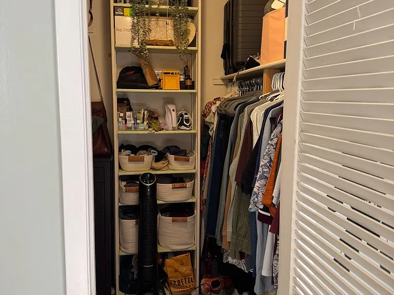 Walk-in closet with additional storage shelves above clothing racks on both sides