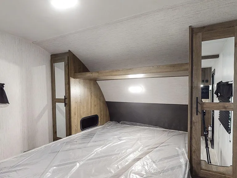 Built-in sleeping nook with an elevated bed platform, overhead lighting, and a mirrored closet for everyday storage.