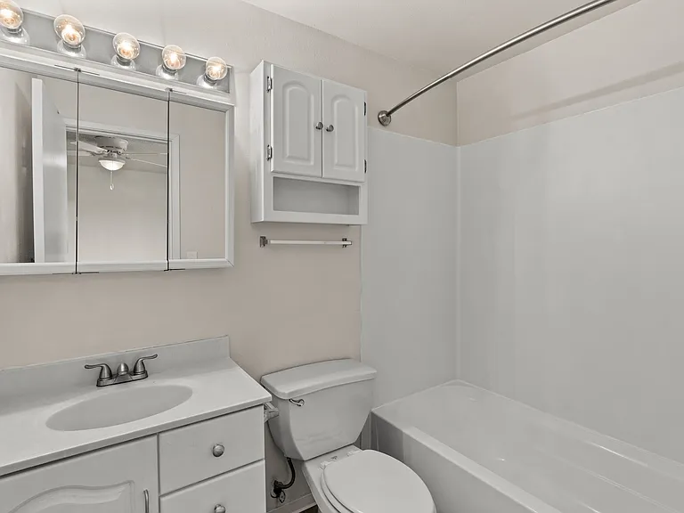 Clean and bright bathroom featuring a full tub, spacious vanity, and extra cabinet storage. Clean and bright bathroom featuring a full tub, spacious vanity, and extra cabinet storage.