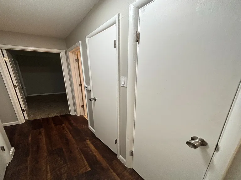 Inviting hallway with sleek hardwood floors and pristine white doors, leading to cozy living spaces.
