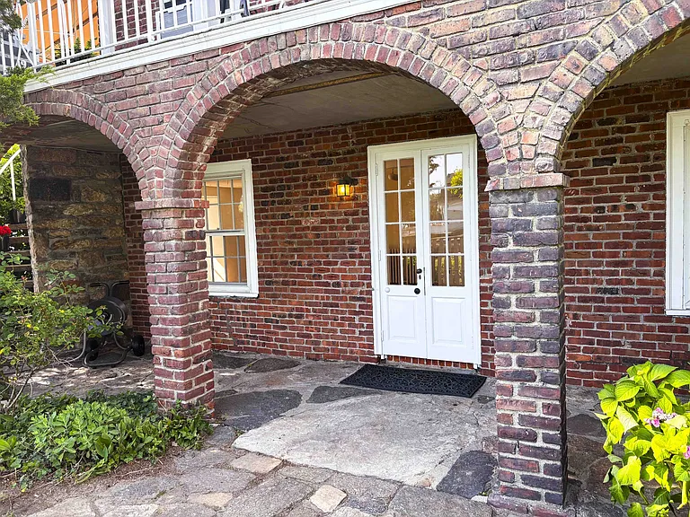 Entrance to apartment via French doors under brick arcade
