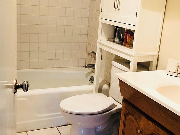 Bath with deep storage cabinets to the left behind door