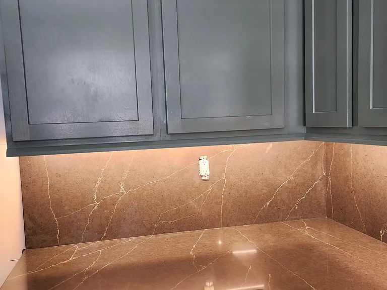 BOOKMARKED QUARTZ AWAITING GOLD AND GLASS DOOR PULLS AND GOLD OUTLET COVERS AND KITCHEN FAUCET