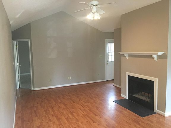 Living room with vaulted ceilings, hardwood laminate floors, and wood fireplace.
