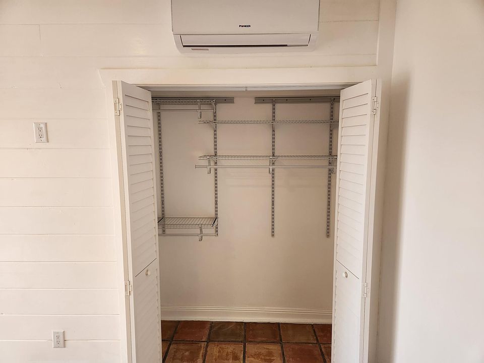 Adjustable closet organization with louvered doors to allow air movement.