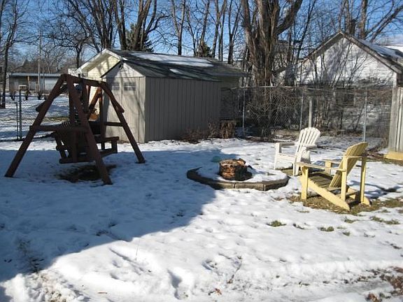 Large fenced backyard with fire pit and storage shed.