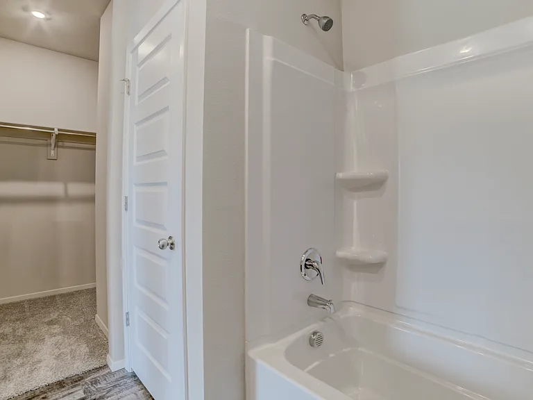 Inside master bathroom looking at walk-in closet and linen closet.