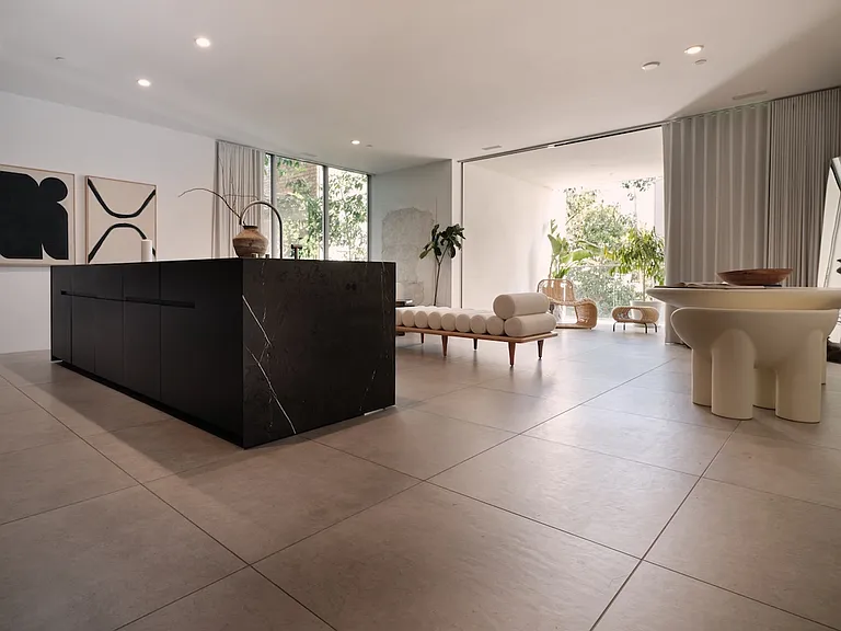 Expansive Open-Concept Living with Seamless Indoor-Outdoor Flow _ This thoughtfully designed space features a striking stone island, oversized floor tiles, and floor-to-ceiling windows that flood the interior with natural light.