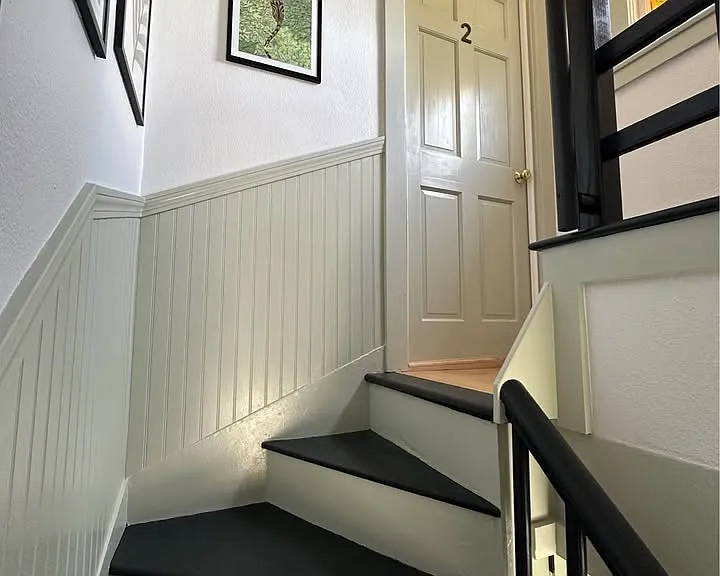 The front door to apartment #2 is located at the top of the stairs. The landing is bright with a window. There is a door opposite that leads to the walk-up attic storage area.