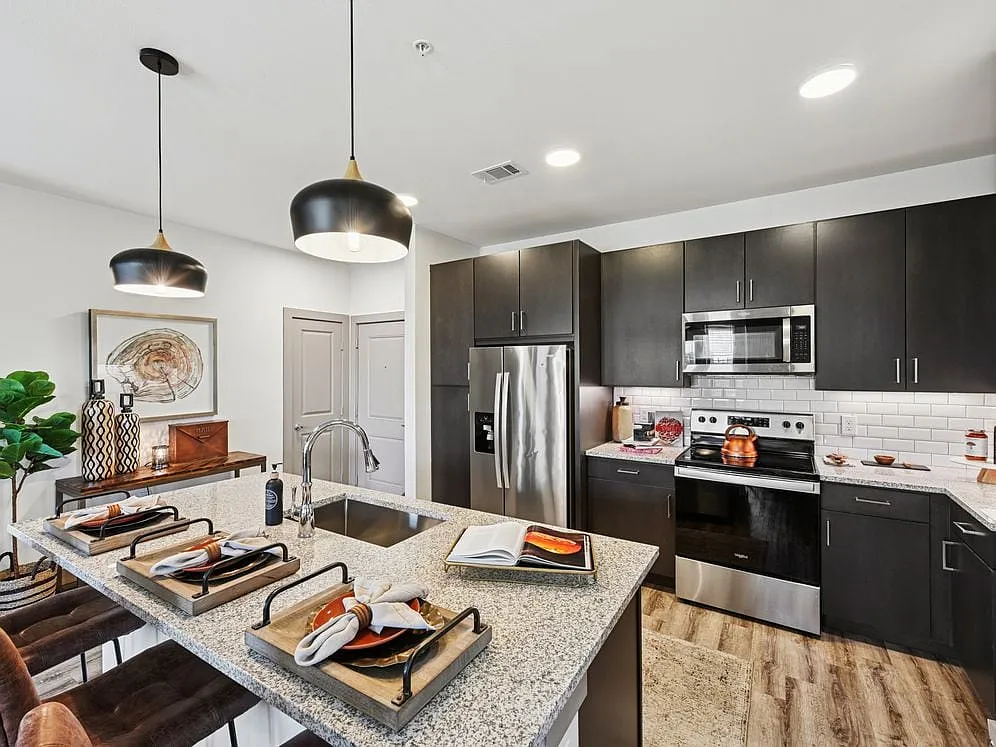 Kitchen with espresso cabinetry, speckled granite countertops, white subway tile backsplash, stainless steel appliances, and hard surface flooring - Avalon Benbrook