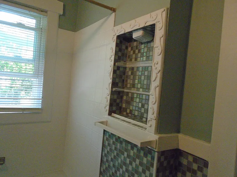Glass-tiled bathroom with large closet and shelfing.