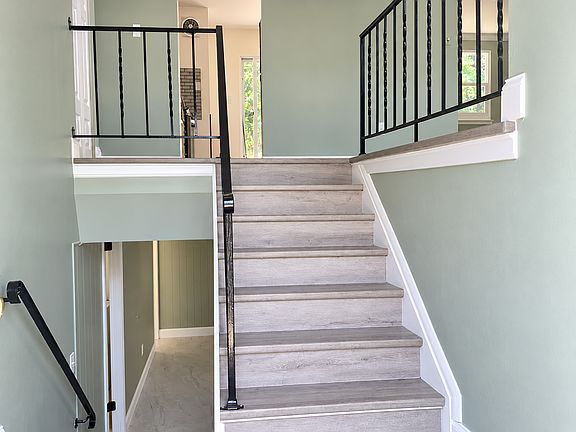 Split-level entrance with updated flooring and black railings.