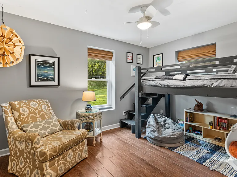 Bedroom #3 with a lofted twin bed, rocking chair, room-darkening shades, dresser, and a ceiling fan.