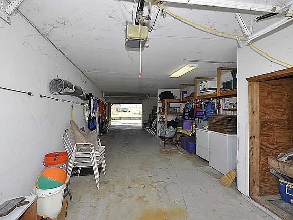 Gigantic three car tandem drive through garage! Washer/Dryer & extra storage located here.  Also has shaded patio under wooden deck with fantastic lake view!