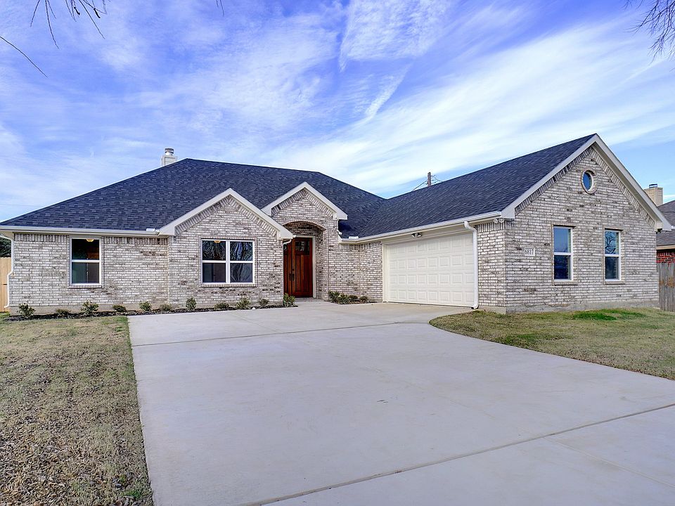 Front view showing large driveway, double front door, and the two car garage.